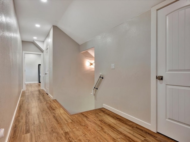 corridor featuring light wood-type flooring and vaulted ceiling