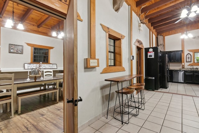 kitchen with dishwasher, sink, vaulted ceiling with beams, wood ceiling, and light hardwood / wood-style floors