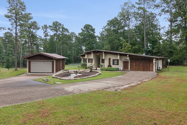 view of front of house with a garage, a front yard, and an outbuilding