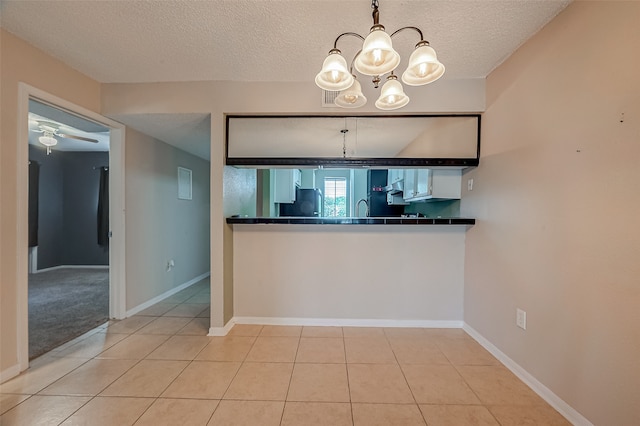 kitchen with hanging light fixtures, light tile patterned flooring, ceiling fan with notable chandelier, a textured ceiling, and sink