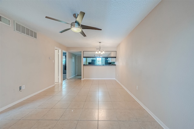 unfurnished room featuring a textured ceiling, ceiling fan with notable chandelier, and light tile patterned floors