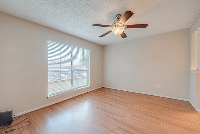 spare room featuring light wood-type flooring, a textured ceiling, and ceiling fan