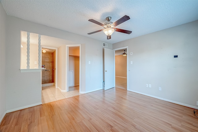 unfurnished room with ceiling fan, a textured ceiling, and light wood-type flooring