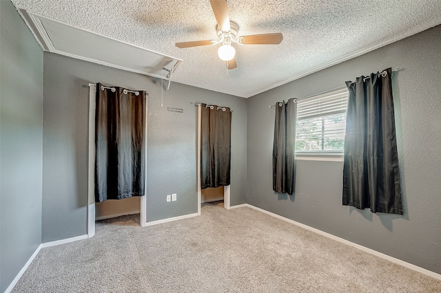 unfurnished bedroom with ceiling fan, light colored carpet, and a textured ceiling