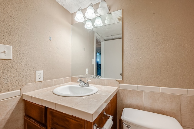 bathroom featuring a textured ceiling, vanity, and toilet