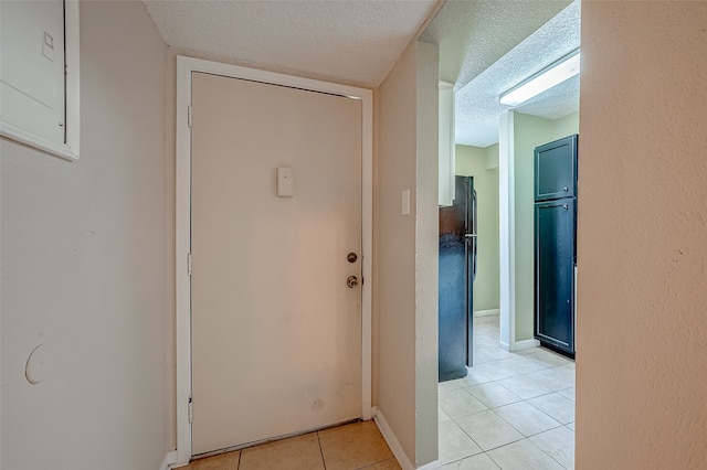 hall with a textured ceiling and light tile patterned floors