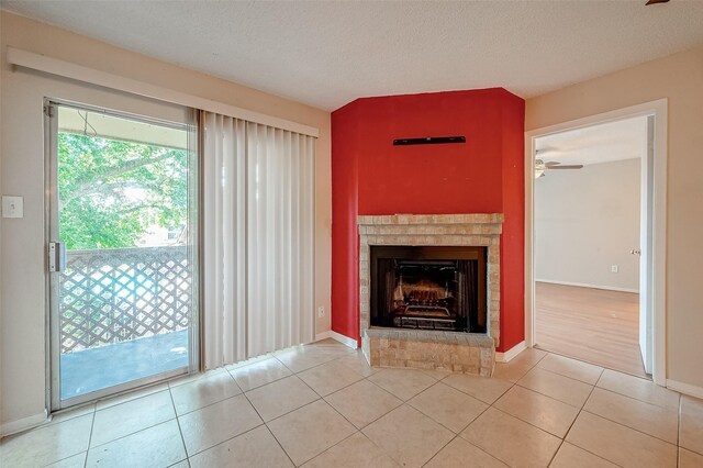 1505 Ward Rd Unit 214, Baytown, TX 77520 - unfurnished living room with a textured ceiling, baseboards, ceiling fan, a fireplace, and light tile patterned floors