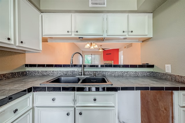 kitchen featuring tile countertops, a chandelier, sink, and white cabinetry