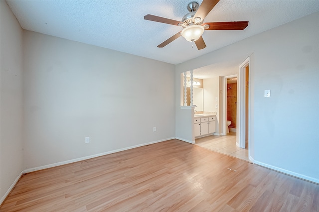 unfurnished bedroom featuring a textured ceiling, ceiling fan, light hardwood / wood-style flooring, and ensuite bath