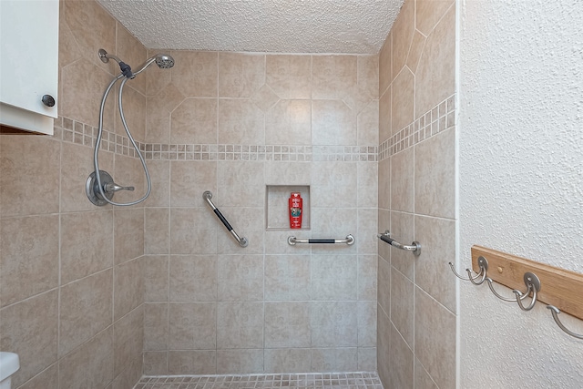 bathroom featuring a textured ceiling and a tile shower