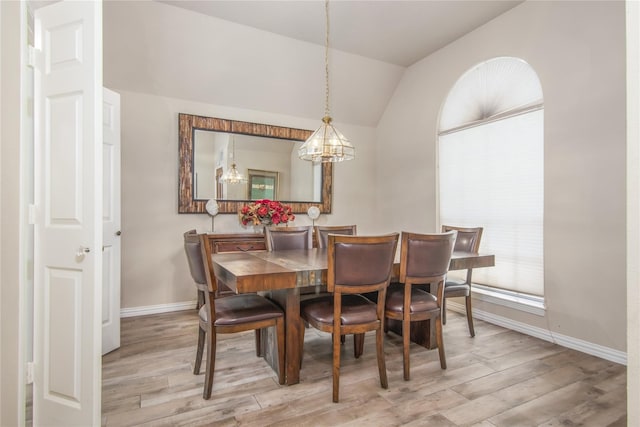 dining room with lofted ceiling, an inviting chandelier, and light hardwood / wood-style floors