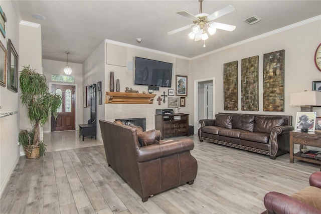 living room featuring crown molding, a fireplace, light hardwood / wood-style flooring, and ceiling fan