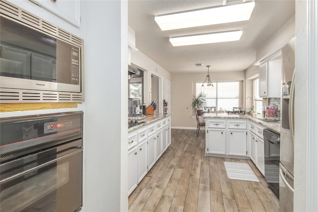 kitchen featuring black appliances, light hardwood / wood-style floors, white cabinets, and pendant lighting