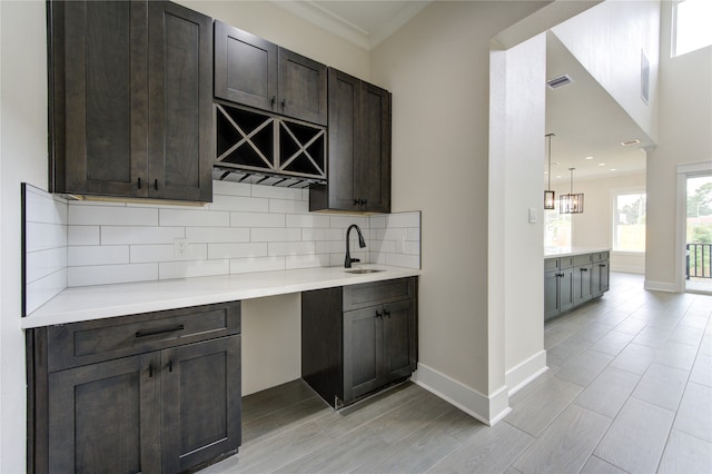 bar featuring crown molding, dark brown cabinetry, decorative backsplash, and light hardwood / wood-style floors