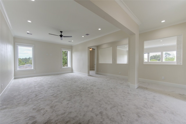 carpeted empty room with a wealth of natural light, ceiling fan, and ornamental molding