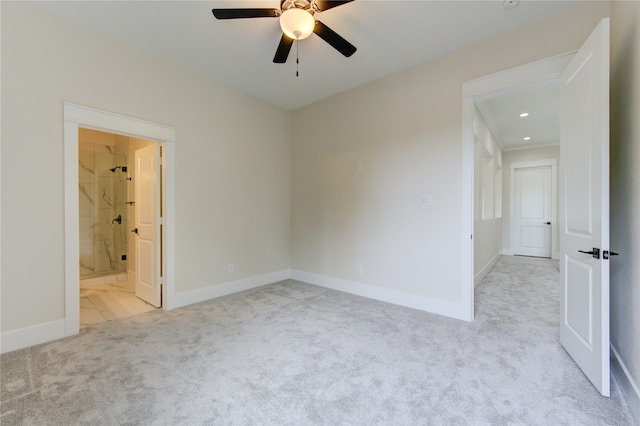 unfurnished bedroom featuring ceiling fan, light colored carpet, and ensuite bath