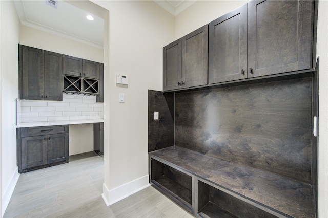 mudroom featuring built in desk, crown molding, and light hardwood / wood-style flooring