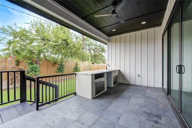 balcony with ceiling fan, sink, an outdoor kitchen, and a patio area