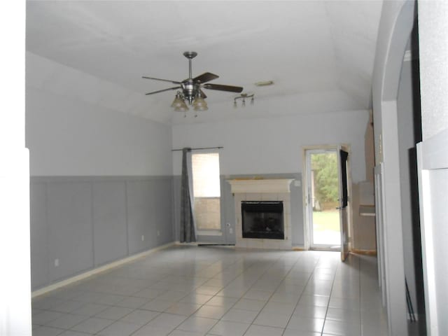 unfurnished living room featuring a fireplace, light tile patterned floors, ceiling fan, and a healthy amount of sunlight