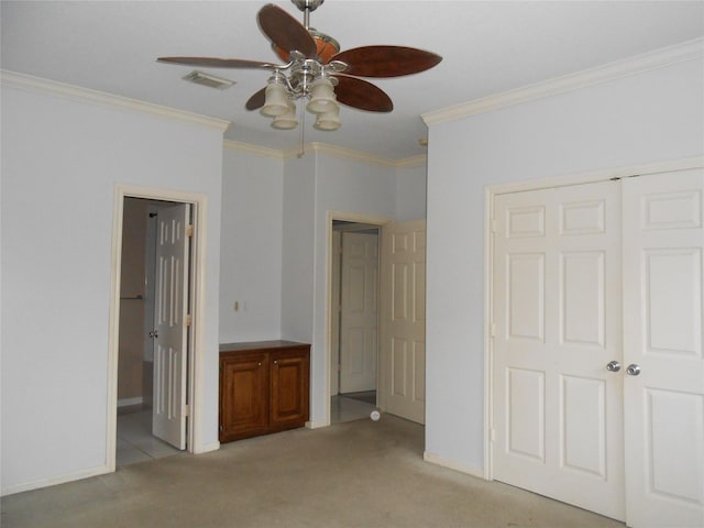 unfurnished bedroom with ensuite bath, ceiling fan, crown molding, light carpet, and a closet