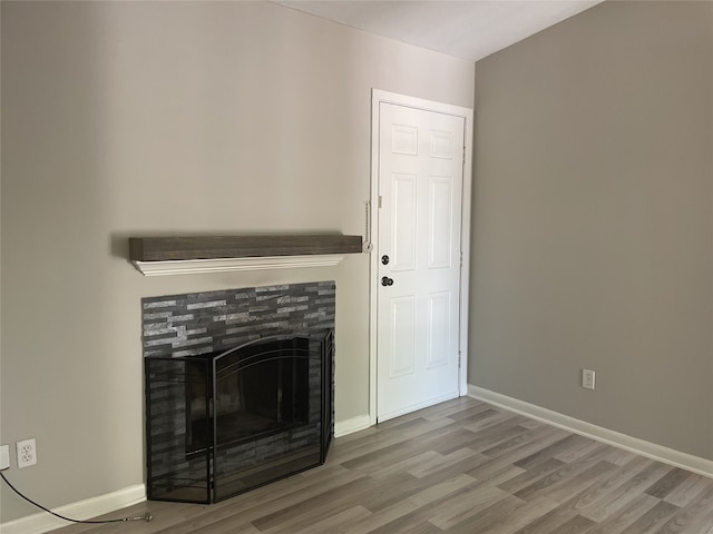 unfurnished living room featuring a tiled fireplace and hardwood / wood-style flooring