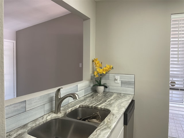 kitchen featuring dishwasher, sink, and light stone countertops