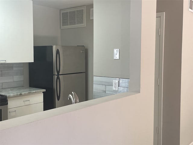 kitchen with white cabinets, stainless steel fridge, sink, and decorative backsplash