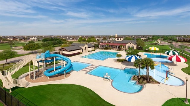 view of swimming pool with a water slide, a patio, and a playground