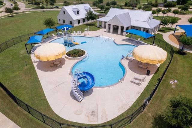 view of swimming pool with a lawn, a water slide, and a patio