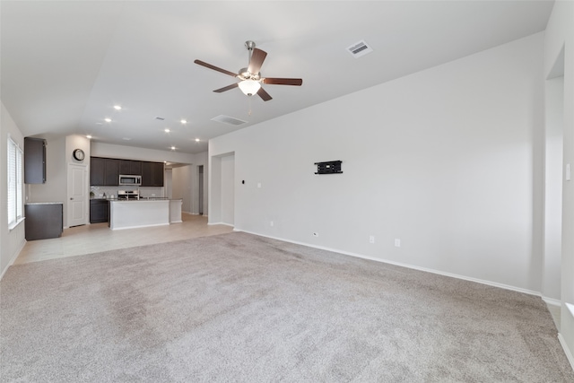 unfurnished living room featuring light carpet, vaulted ceiling, and ceiling fan