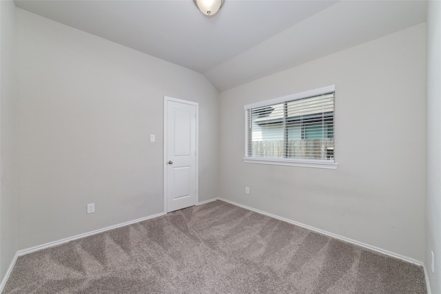 carpeted empty room featuring vaulted ceiling