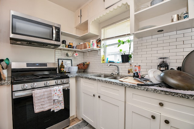 kitchen with light stone counters, sink, appliances with stainless steel finishes, and white cabinets