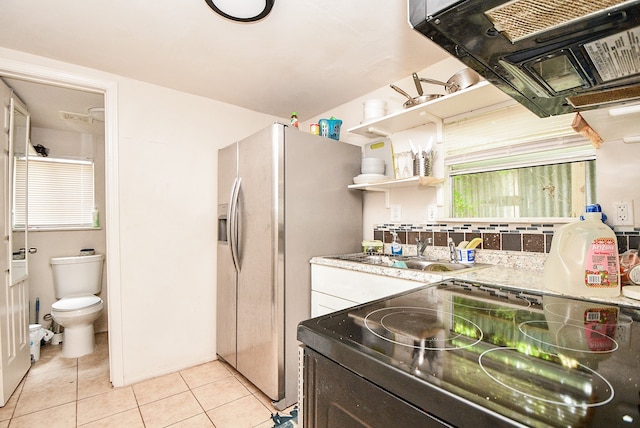 kitchen with light tile patterned floors, sink, stainless steel fridge, exhaust hood, and range