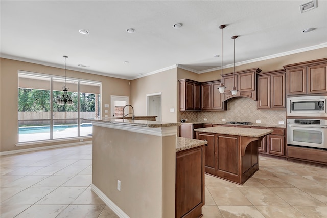 kitchen with decorative light fixtures, appliances with stainless steel finishes, light tile patterned floors, and a kitchen island with sink