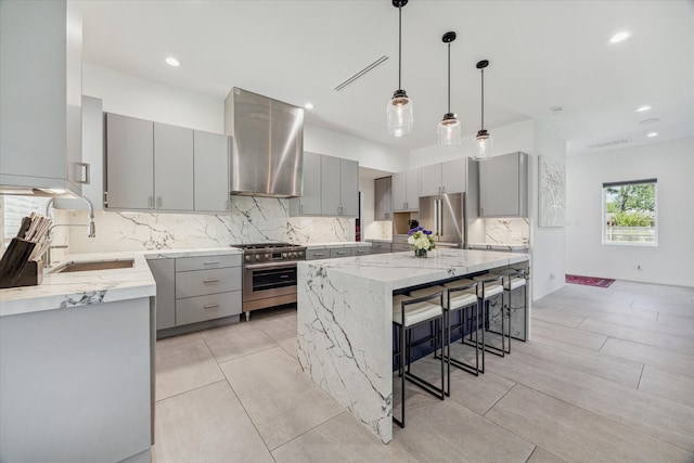 kitchen featuring sink, wall chimney range hood, gray cabinets, a spacious island, and premium appliances