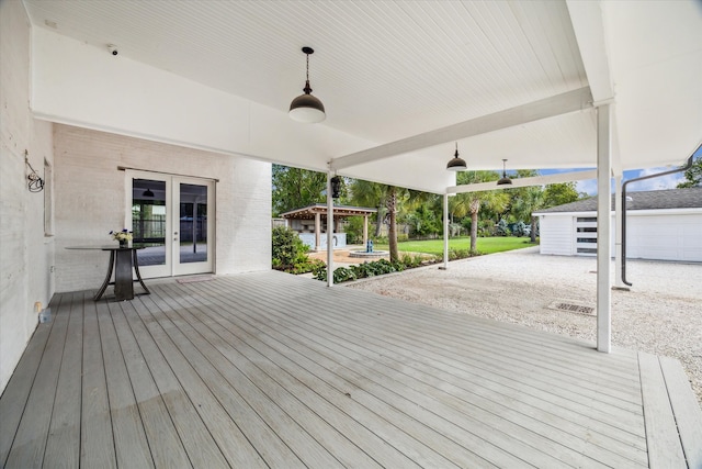 wooden terrace featuring an outdoor structure, a garage, french doors, and ceiling fan