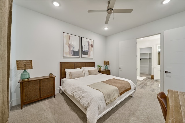 bedroom featuring light carpet, a spacious closet, ceiling fan, and a closet