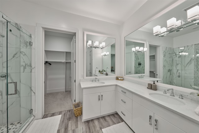 bathroom with hardwood / wood-style floors, an enclosed shower, an inviting chandelier, and vanity