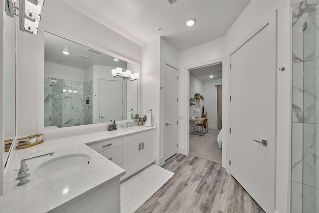 bathroom featuring wood-type flooring, an enclosed shower, a notable chandelier, and vanity