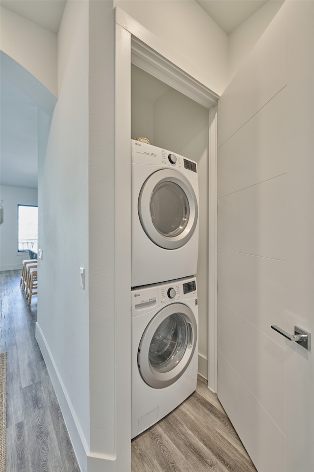 laundry area with stacked washer / dryer and light hardwood / wood-style floors