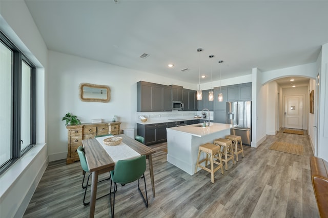 kitchen with a kitchen island with sink, hardwood / wood-style flooring, stainless steel appliances, and sink