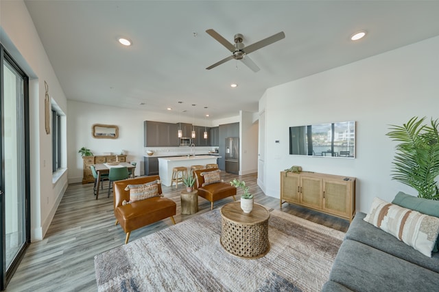 living room featuring light hardwood / wood-style flooring, sink, and ceiling fan