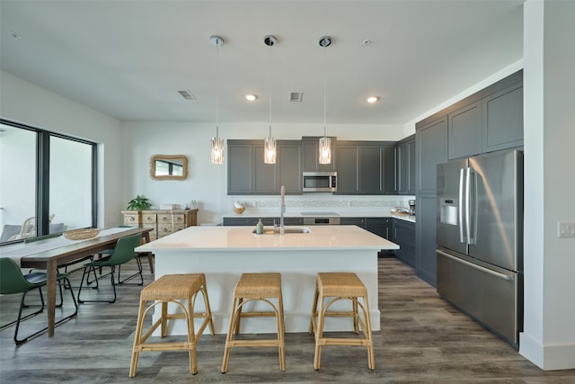 kitchen featuring dark wood-type flooring, sink, decorative light fixtures, and appliances with stainless steel finishes