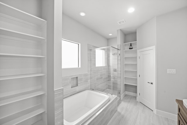 bathroom with plus walk in shower, hardwood / wood-style flooring, and vanity