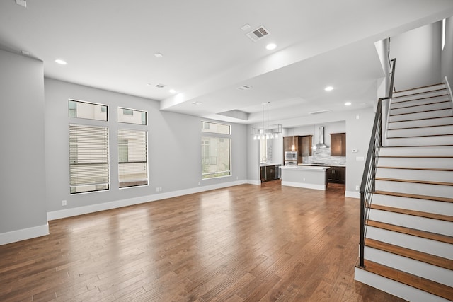 unfurnished living room featuring a notable chandelier and dark hardwood / wood-style flooring