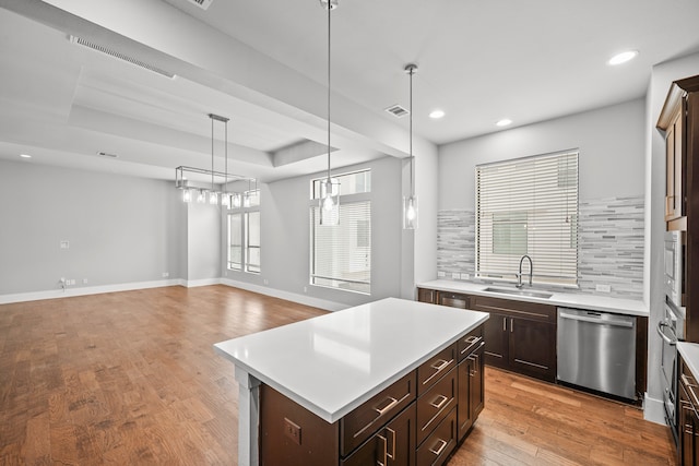 kitchen featuring tasteful backsplash, a kitchen island, stainless steel appliances, decorative light fixtures, and sink