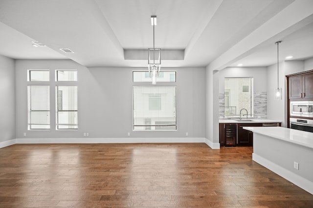 interior space featuring appliances with stainless steel finishes, hanging light fixtures, dark brown cabinetry, and dark hardwood / wood-style floors