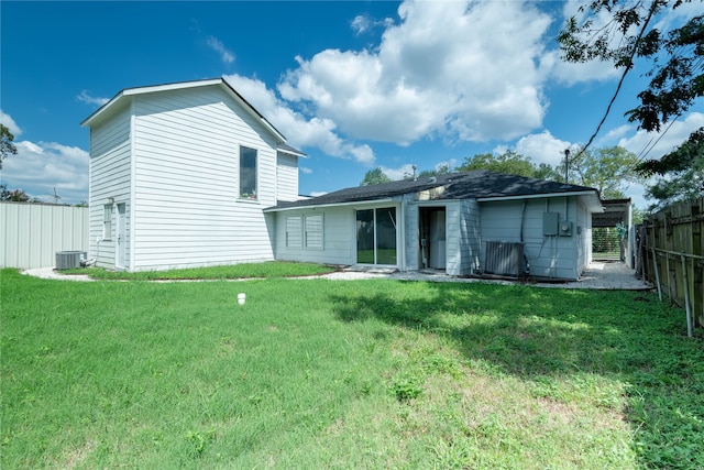 rear view of house featuring cooling unit and a lawn