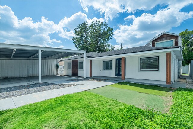 exterior space with a front lawn, a carport, and stucco siding