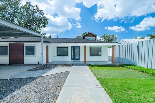 view of front facade featuring stucco siding, a shingled roof, a front lawn, and fence